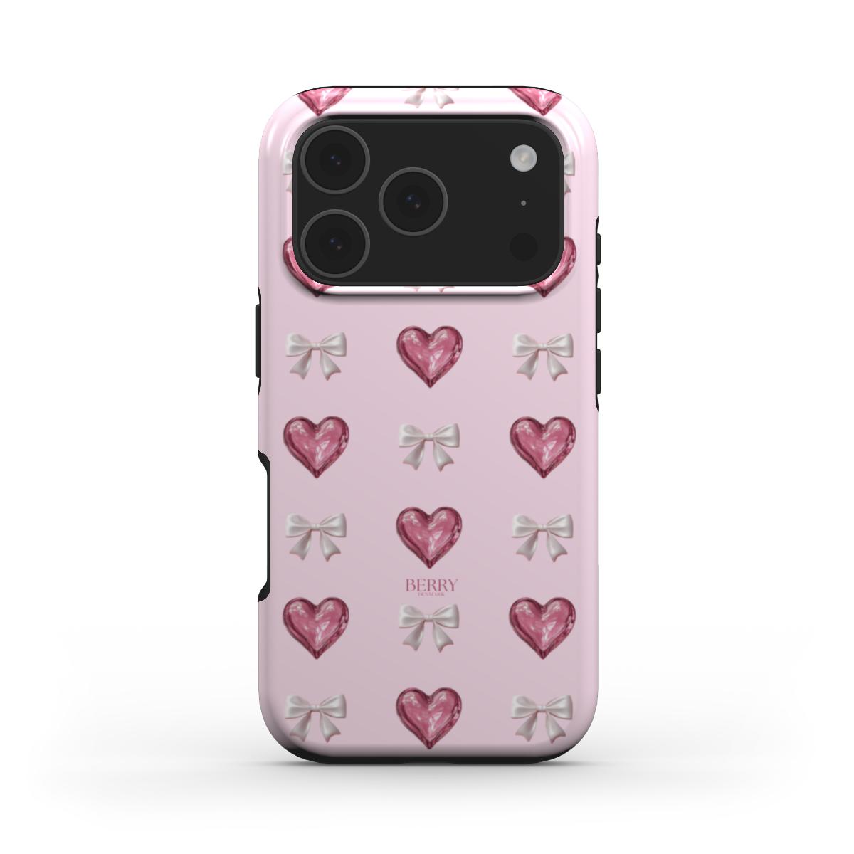 Pink phone case with glossy pink hearts and silver bows on a flerfarvet background, creating a trendy feminine and girly aesthetic.