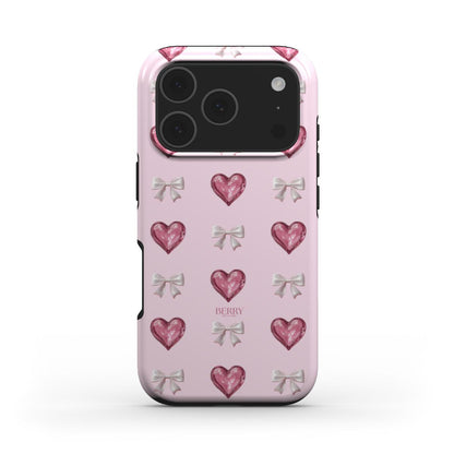 Pink phone case with glossy pink hearts and silver bows on a flerfarvet background, creating a trendy feminine and girly aesthetic.